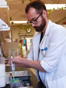 Kyle Card inspects a petri dish.