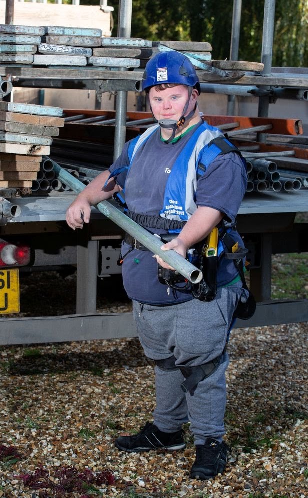 Picture of Todd Scanlon on a worksite with full safety gear and holding a scaffold component pipe.