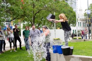 A woman in a park pours a bucket of water during a charity challenge