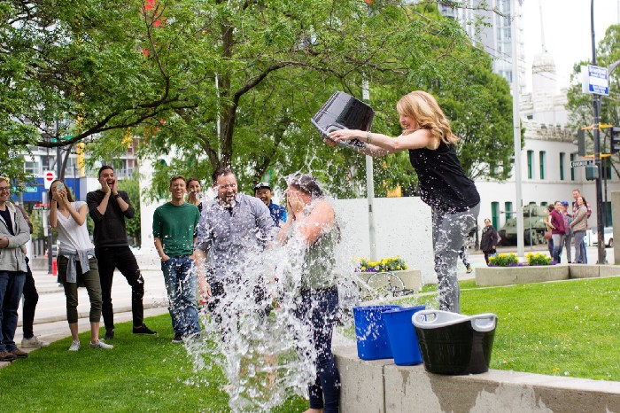 Picture of a woman dumping a large bucket of water onto another woman.