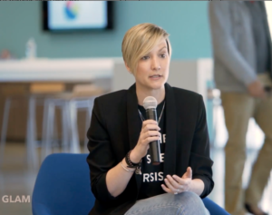 Kr Liu young short haired blonde woman business casual speaking into handheld microphone while seated