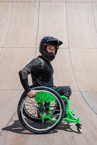 Picture of Aaron Fotheringham posing next to a ramp in his wheelchair with a helmet on 