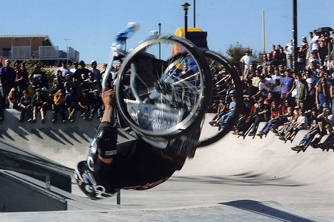 Picture of Aaron Fotheringham doing a backflip in a skatepark on his wheelchair 