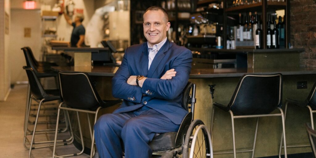picture of Yannick Benjamin sitting in wheelchair next to a bar in a restaurant accessible for people with disability's 