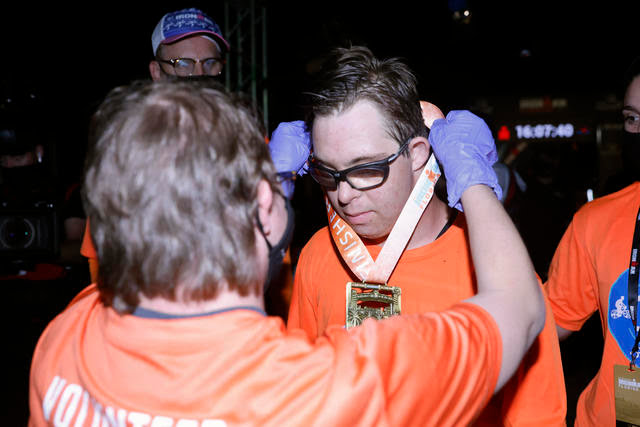 Chris Nikic receiving a medal after finishing ironman triathlon.