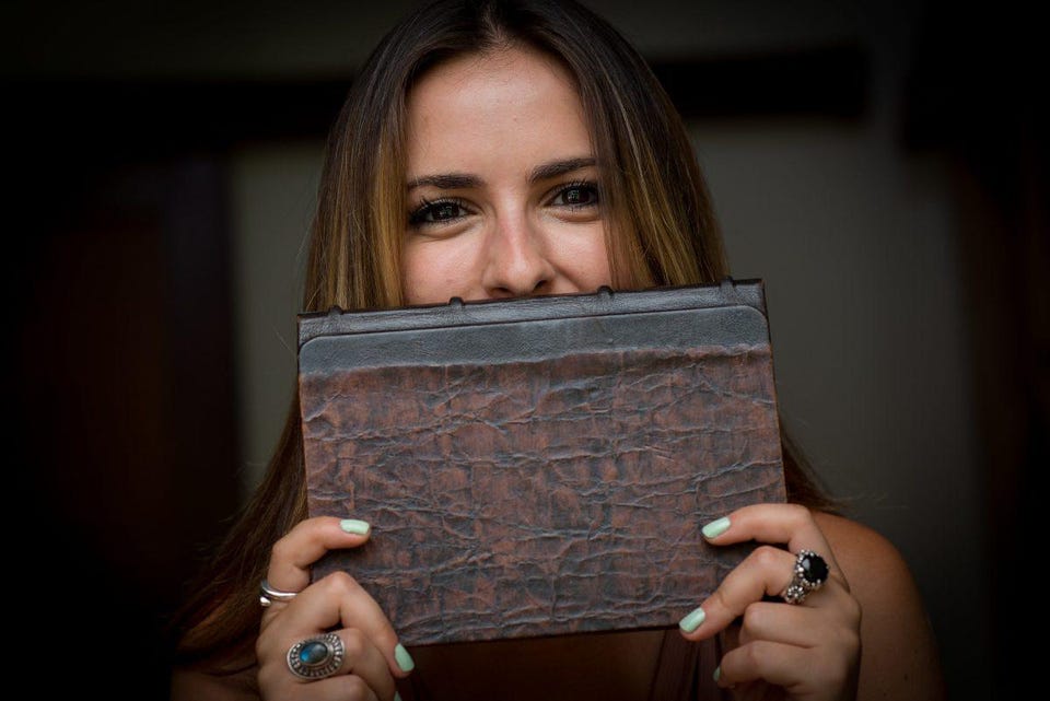 Celinne Da Costa holding up a book in front of her mouth.