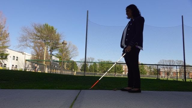 Picture of Jessica Karim walking down a sidewalk using her white cane.