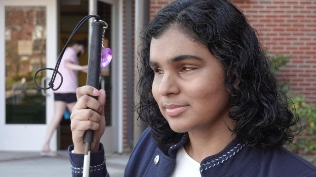 Close up picture of Jessica Karim holding her white cane.