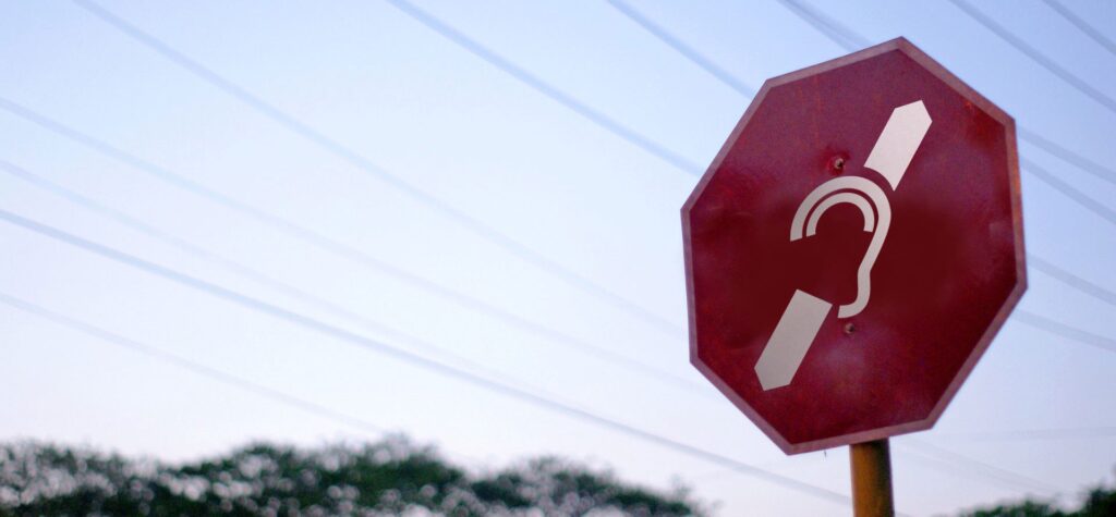 Picture of a stop road sign with the deaf symbol.