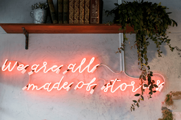 A picture of a neon sign that says "We are all made of story's".