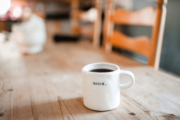 Picture of a white coffee mug with the writing "Begin." on the front.