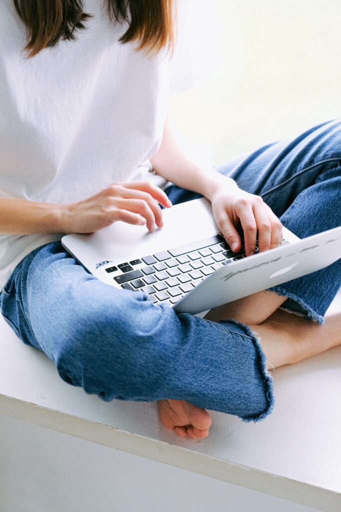 A picture of a woman sitting down typing on her laptop.