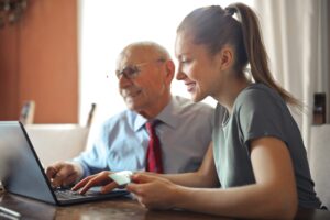 Picture of a younger woman helping an older man.