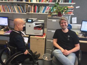 Picture of Tom Shakespeare at his work office with a friend.