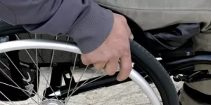 Picture of a guys hand on a wheelchair wheel.