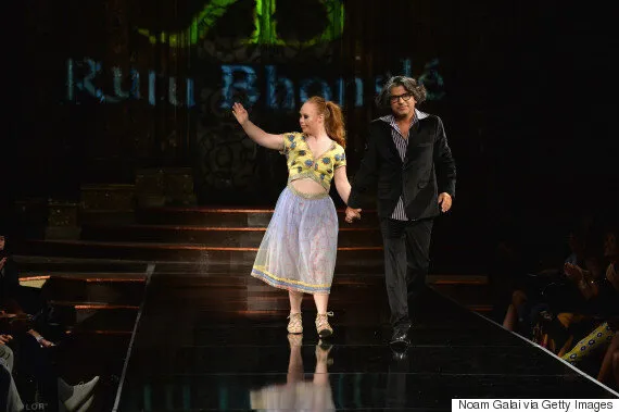 Picture of a woman and man walking down a runway stage.