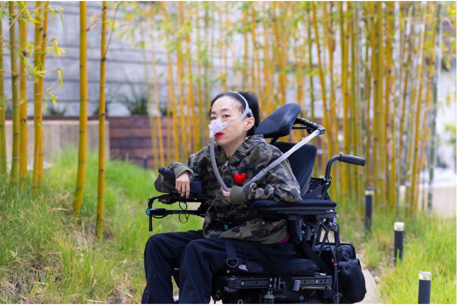 Picture of Alice Wong in her wheelchair outside.