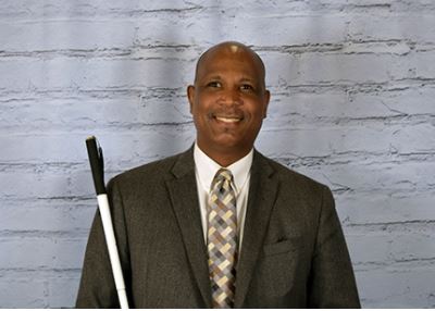 Picture of a blind man holding his white cane.