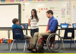 Picture of two kids talking to a man in a wheelchair.