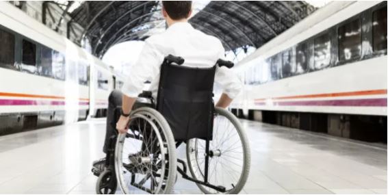 Picture of a guy in his wheelchair in a train station.