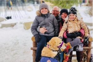 Picture of Kat Anderson and family, clockwise from left: daughter Poppy, dad George, mom Kat, son Atlas, and Atlas' service dog.