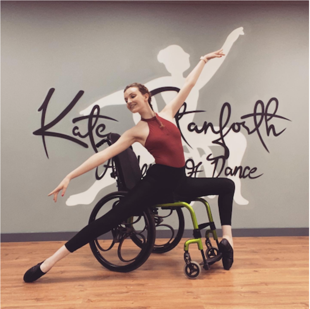 Picture of Kate Stanforth in her wheelchair making a dance pose.