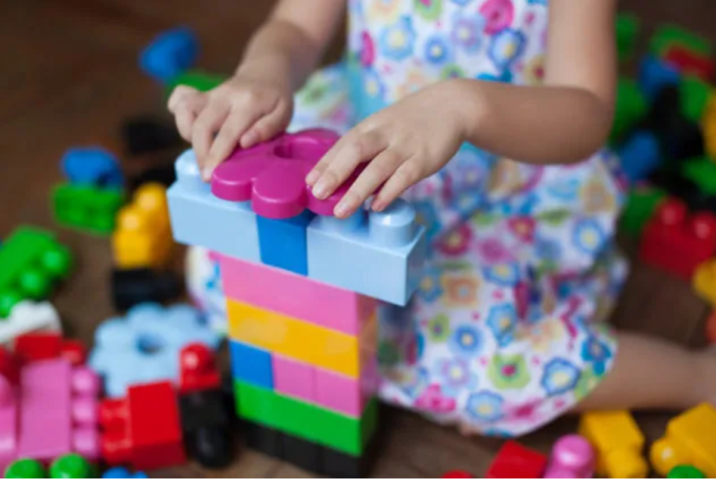 Picture of a little girl playing with lego blocks.