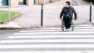 Picture of a man in his wheelchair crossing a road.