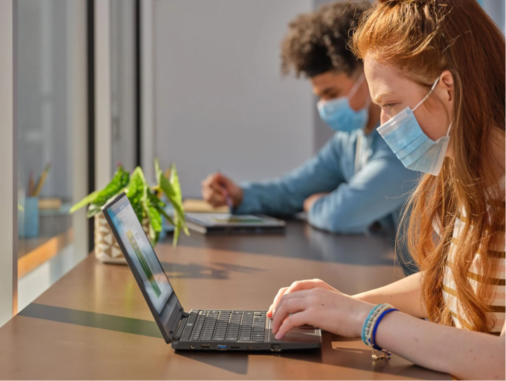 Picture of a teenage girl sitting at a table using a laptop.