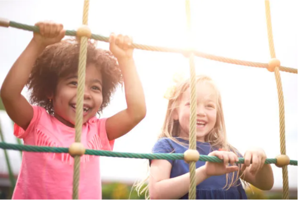 Picture of two young girls playing together on a playground.