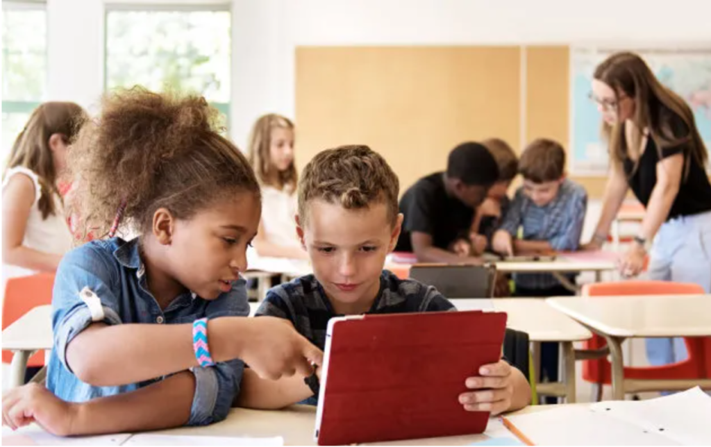 Picture of two young kids using an ipad at school together.