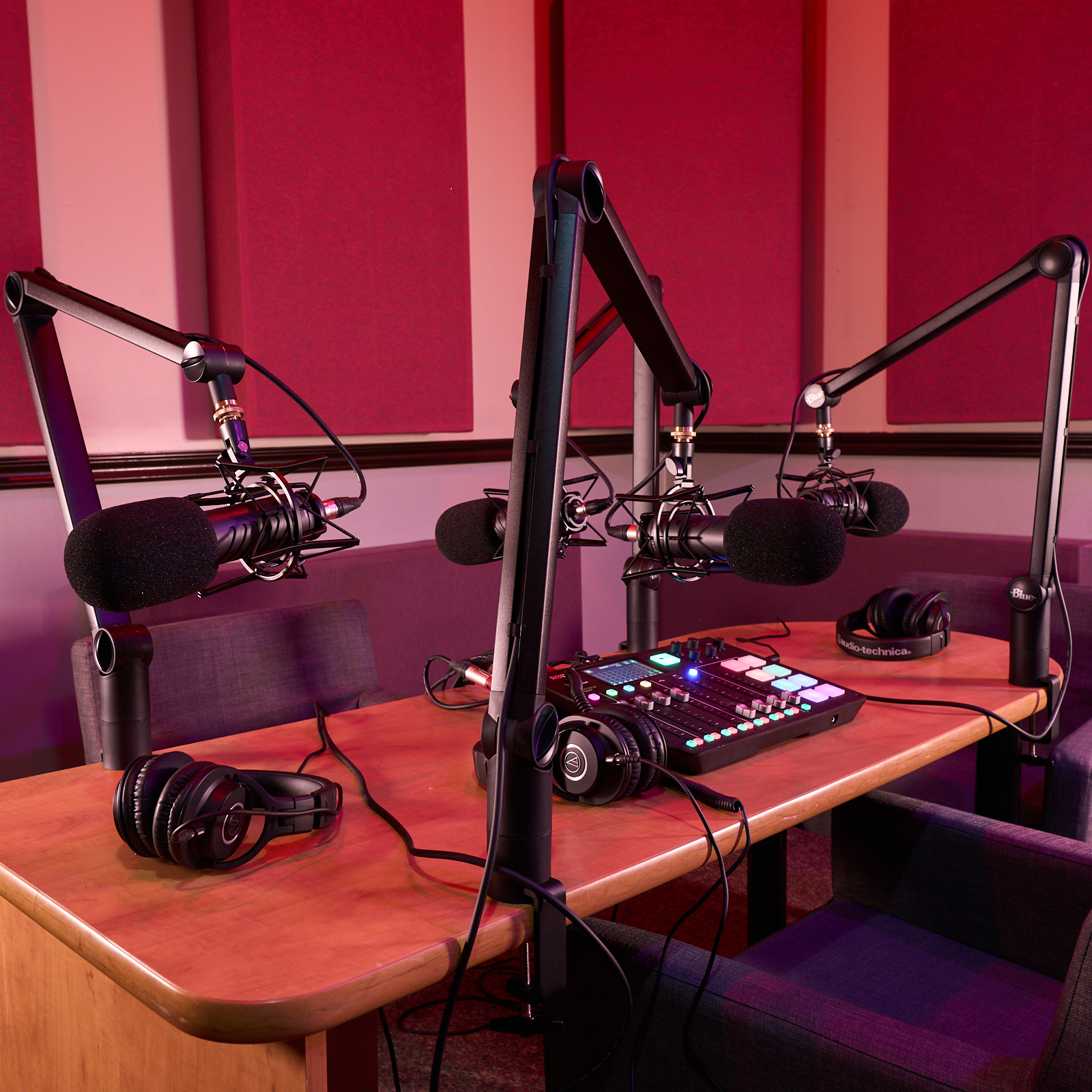 ALWL Podcast Room studio table with microphones on stands and acoustic insulation on walls.