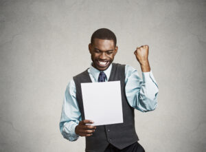 Closeup portrait happy excited young business man executive looking monthly statement glad to pay off bills isolated grey background. Positive emotion facial expression. Financial success good