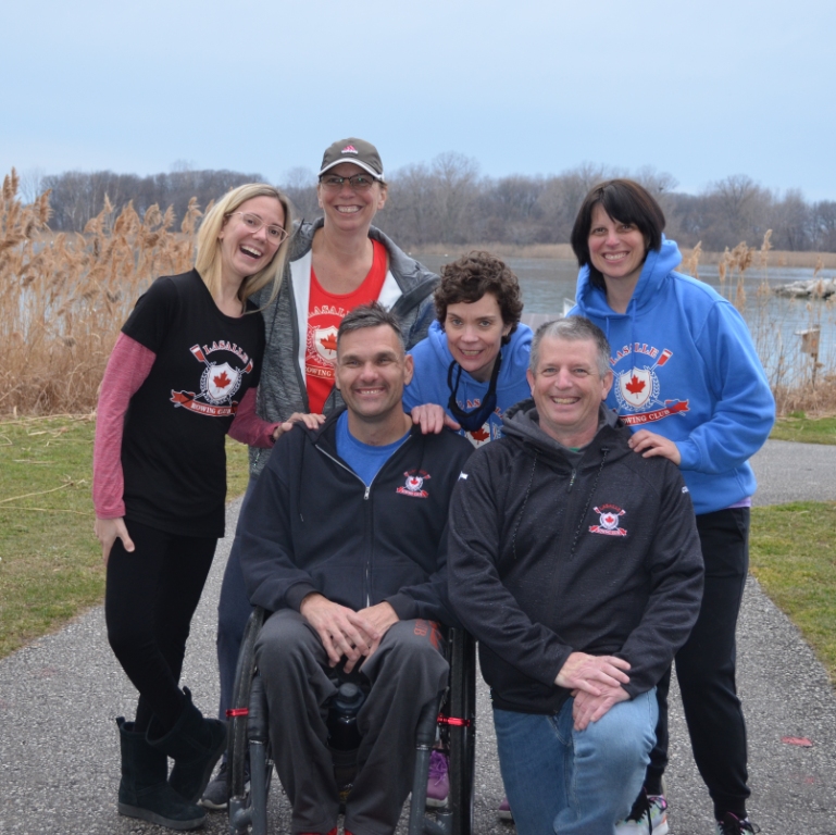 A group of smiling people in athletic wear one person is in a wheelchair.
