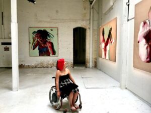 Kam Redlawsk in a wheel chair looking at art in a gallery.