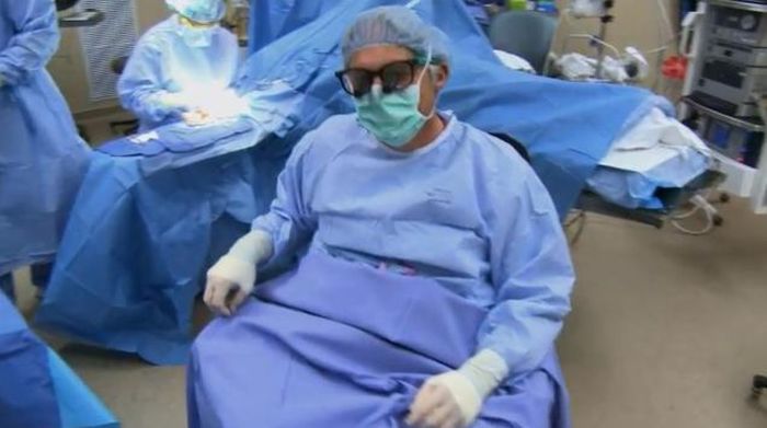 Dr. Rummel in full scrubs seated in the operating theatre.