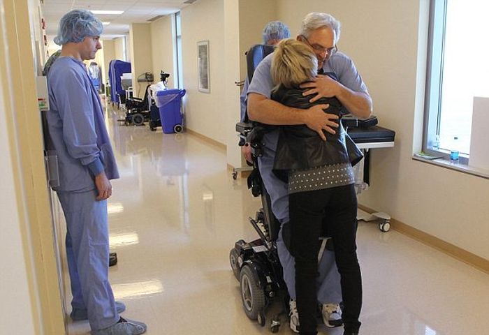 Dr. Rummel hugging a person in a hallway of a hospital from his standing wheelchair.