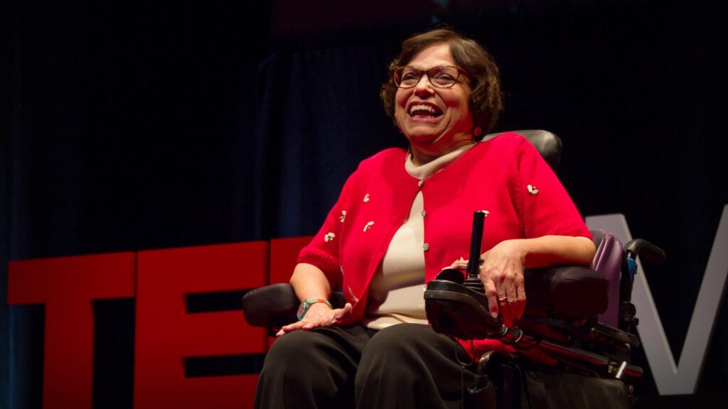 Judith Heumann smiles on stage at a Ted Talks.