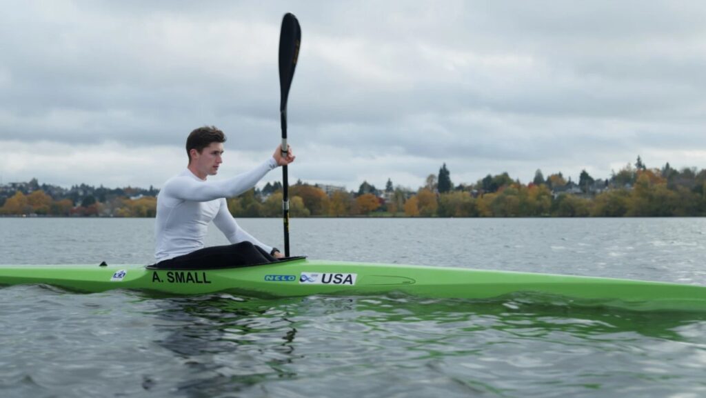 Aaron Small paddles through the water in a  a green kayak.